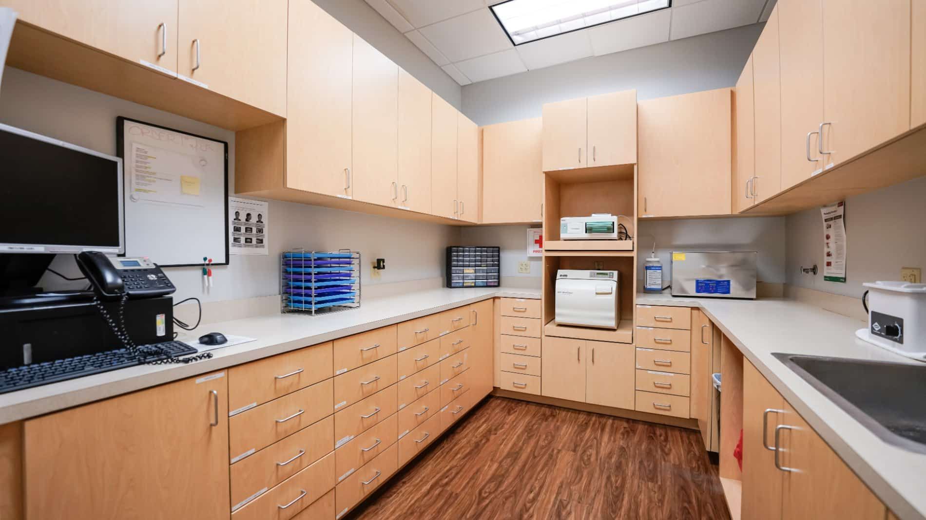 A kitchen with wooden cabinets , a sink , and a computer.