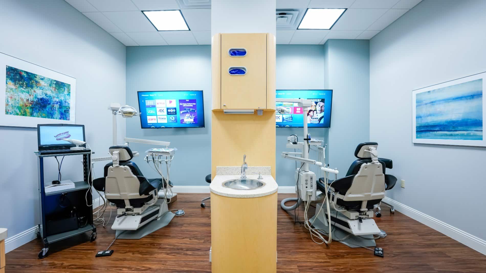 A dental office with two dental chairs and a sink.