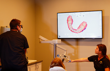 A dentist is giving a presentation to a patient in a dental office.