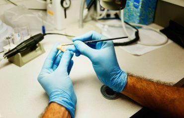 A person wearing blue gloves is working on a piece of equipment.