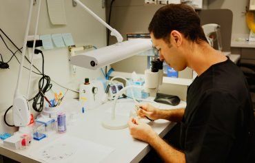 A man is working at a desk in a dental lab.
