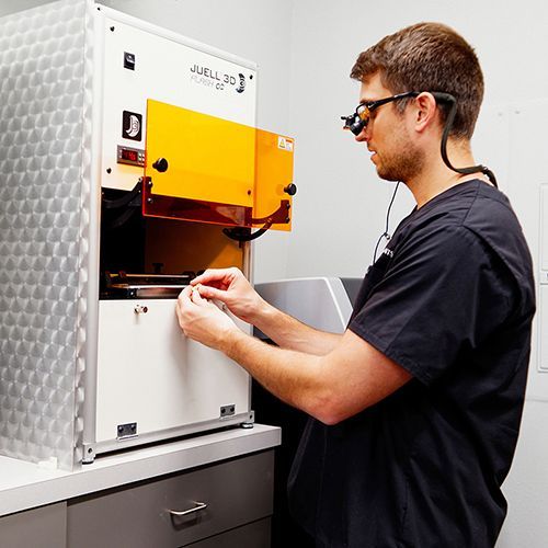 A man wearing goggles is working on a machine.