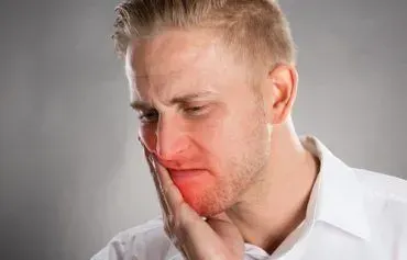 A woman is brushing her teeth with a blue toothbrush.
