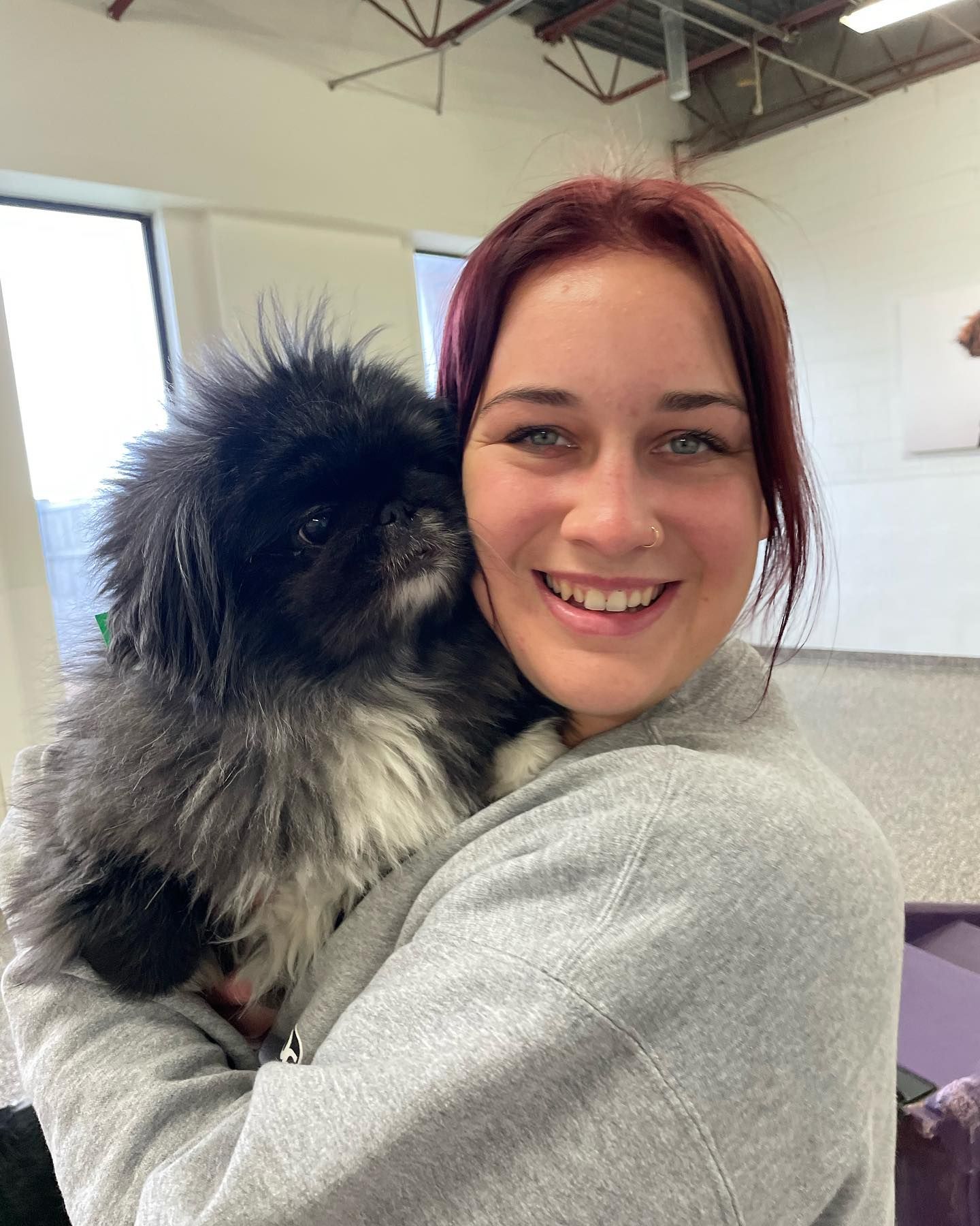 A woman is holding a small black and white dog in her arms.