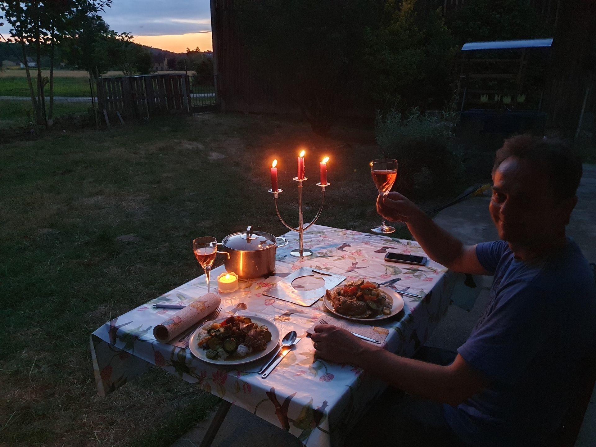 Een man zit in het donker aan een tafel met kaarsen en borden met eten
