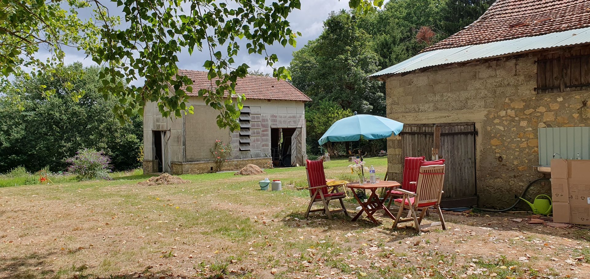 A table and chairs are sitting in front of a stone barn.