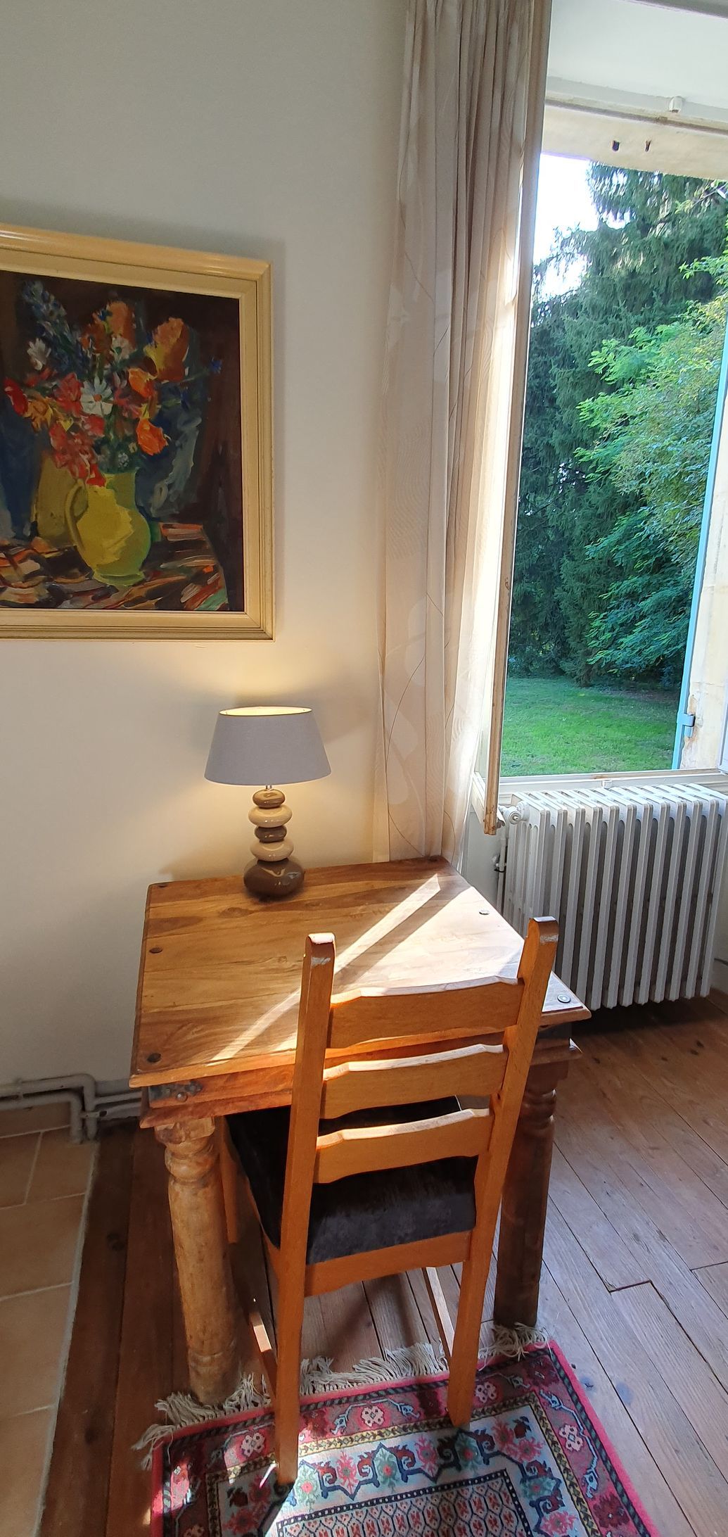 Een houten bureau in het zonlicht met een lamp en een schilderij aan de muur erboven
