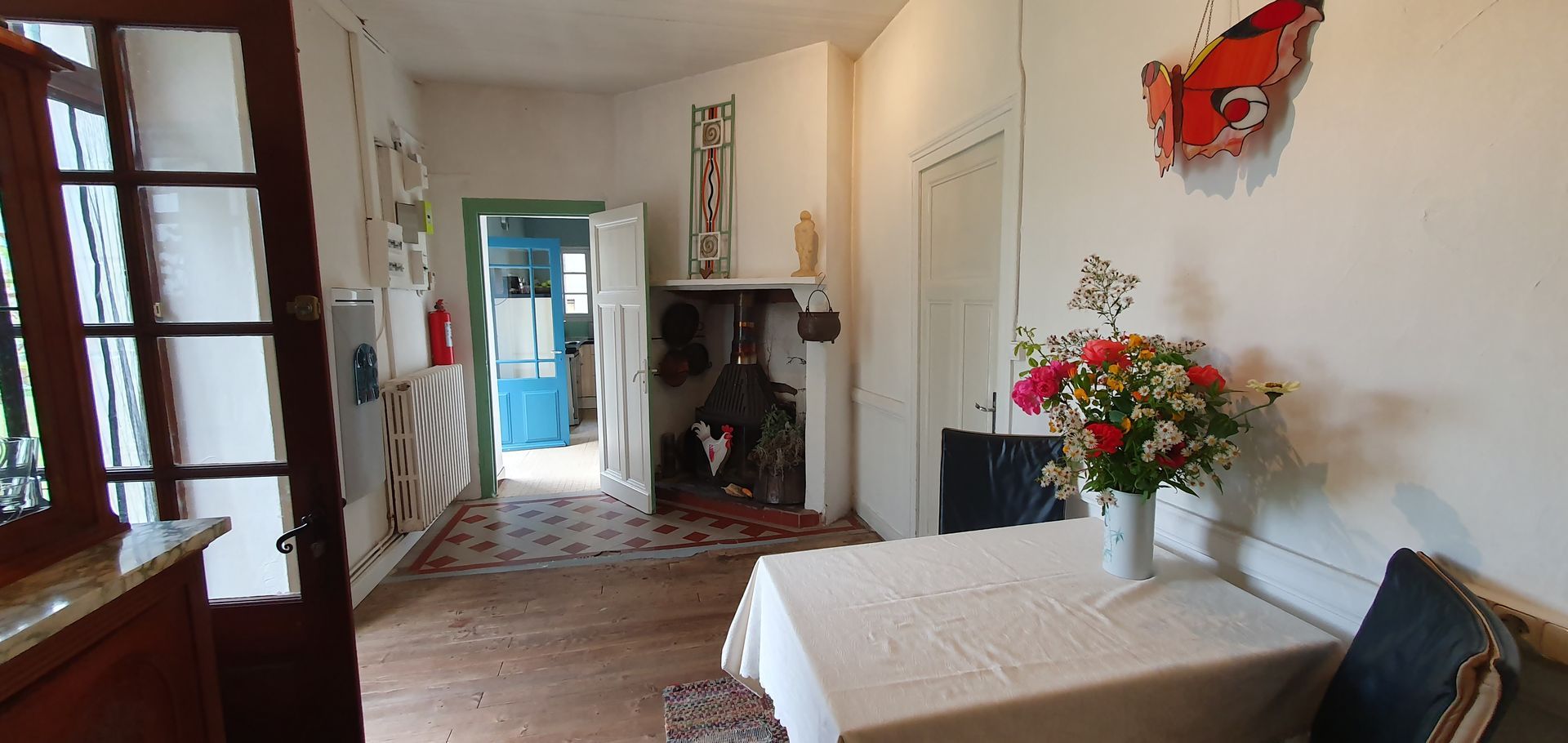 Een kamer met een tafel en stoelen en een vlinder aan de muur