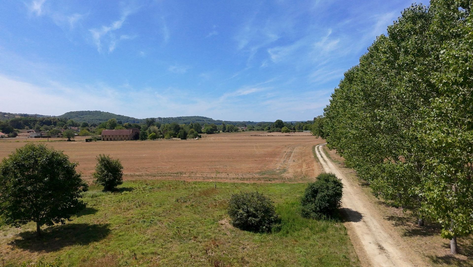Een huis met blauwe luiken en roze bloemen staat achter een smeedijzeren hek
