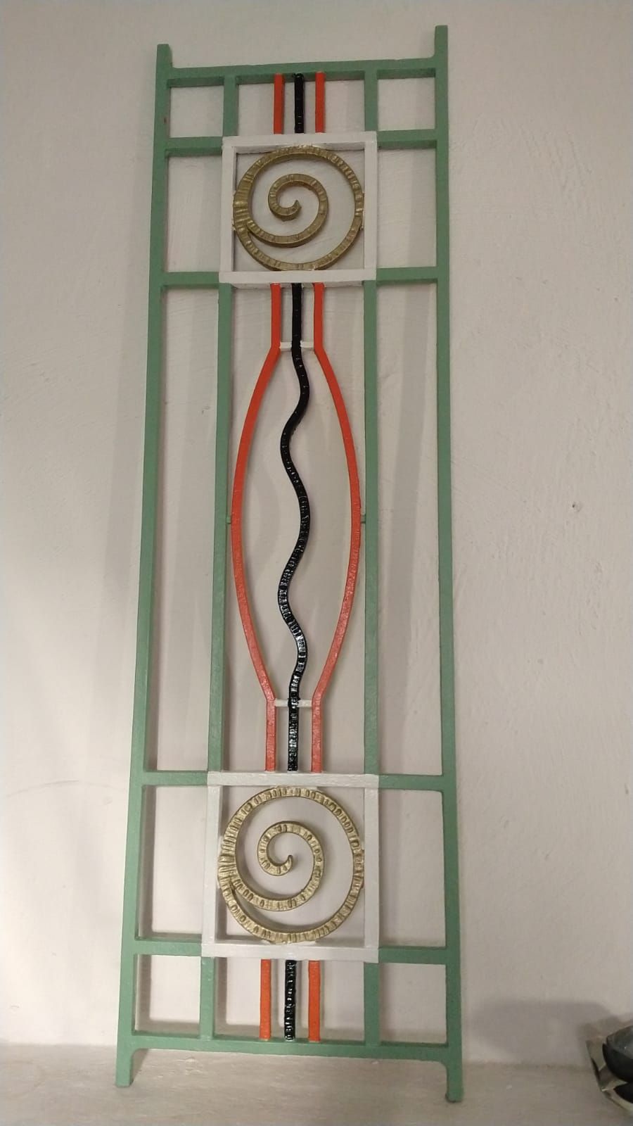 Een groene kleurig hekwerk met een spiraalvormig ontwerp erop