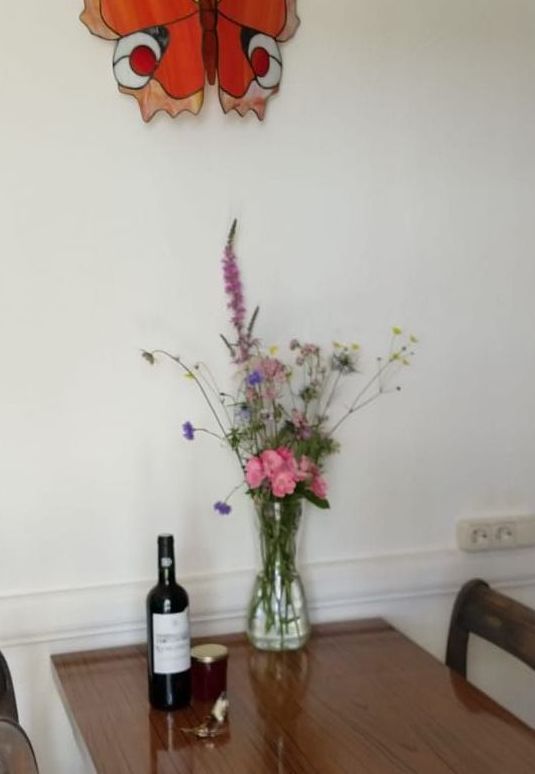 A table with a vase of flowers and a bottle of wine