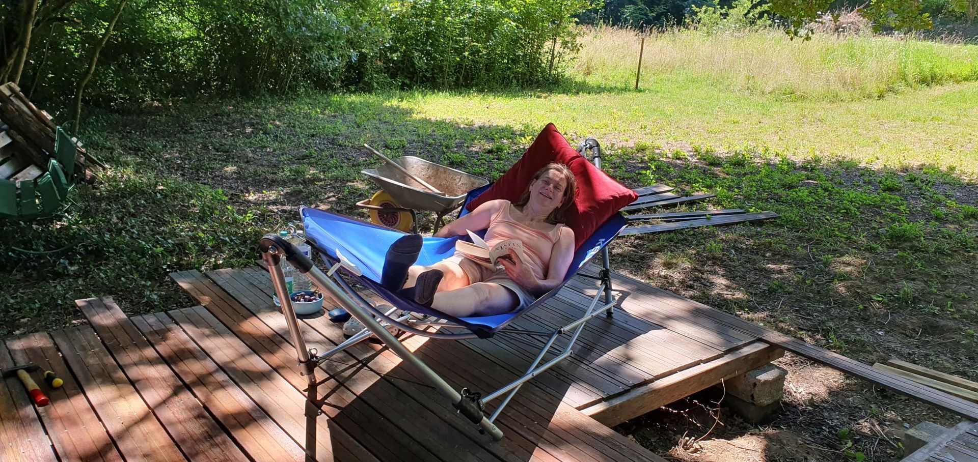 Person relaxing in a blue hammock, outside on a wooden deck.