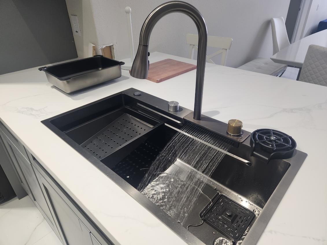 Black kitchen sink with faucet, drainboard, and dish washer in a white countertop.