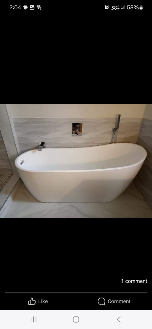 A white freestanding bathtub in a bathroom, with a faucet on the wall.
