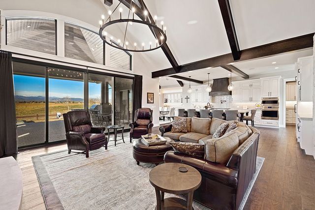A living room with a couch , chairs , tables and a chandelier.
