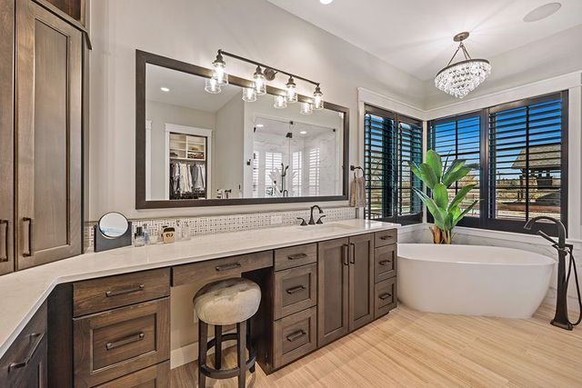 A bathroom with two sinks , a tub , and a large mirror.