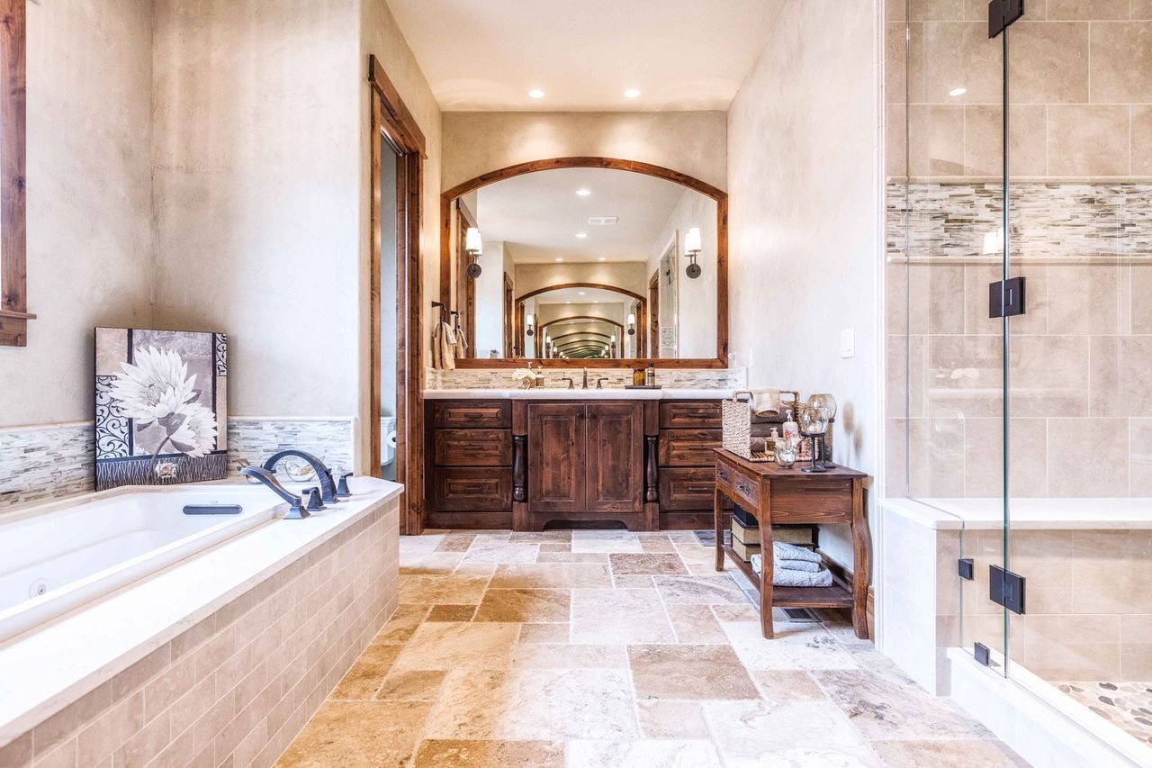 A bathroom with a tub , sink , mirror and shower.