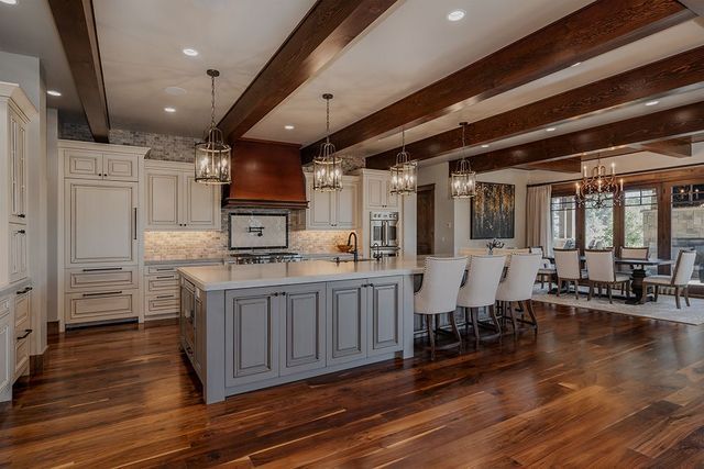A large kitchen with a large island in the middle and wooden beams.