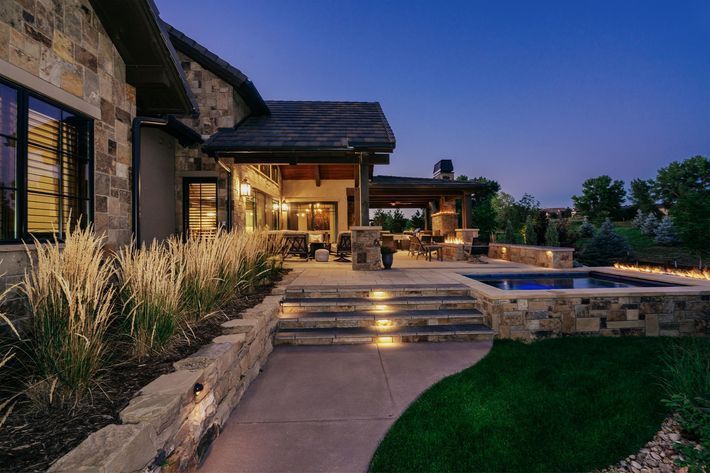 A large stone house with a pool and stairs leading to it at night.