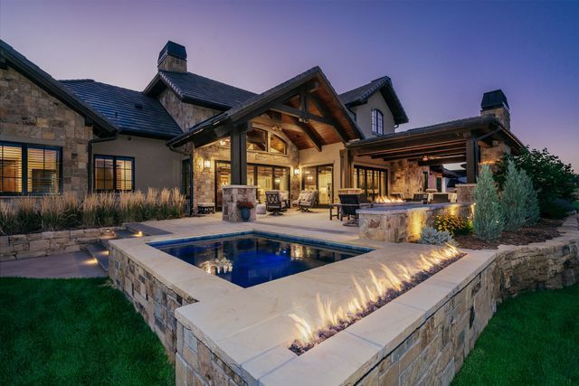 A large house with a swimming pool and a fire pit in front of it.