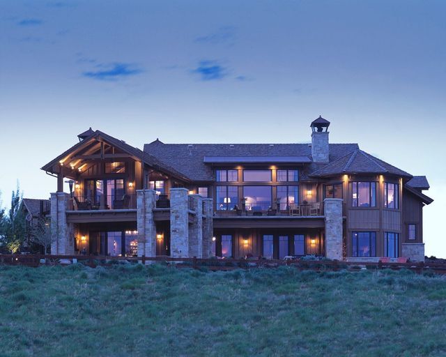 A large house sits on top of a grassy hill at night