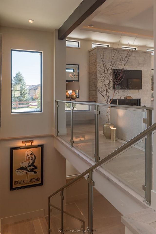A staircase in a house with a glass railing and a picture on the wall.