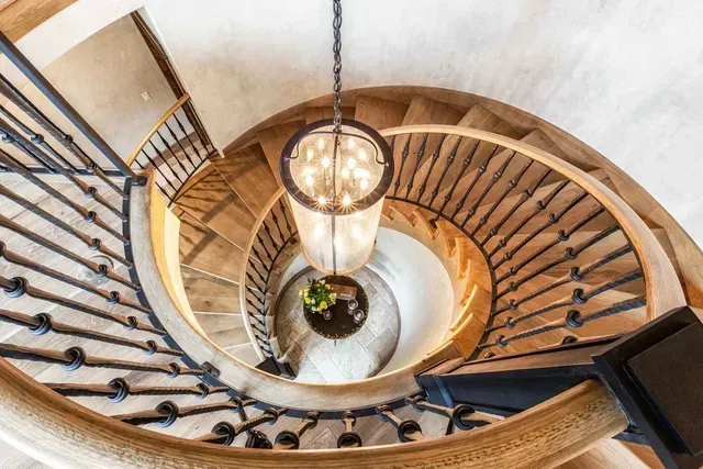A spiral staircase with a chandelier hanging from the ceiling.