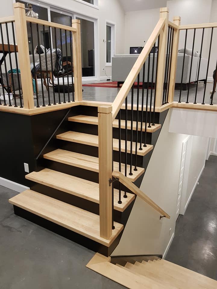 Un escalier en bois avec rampes noires dans un salon.