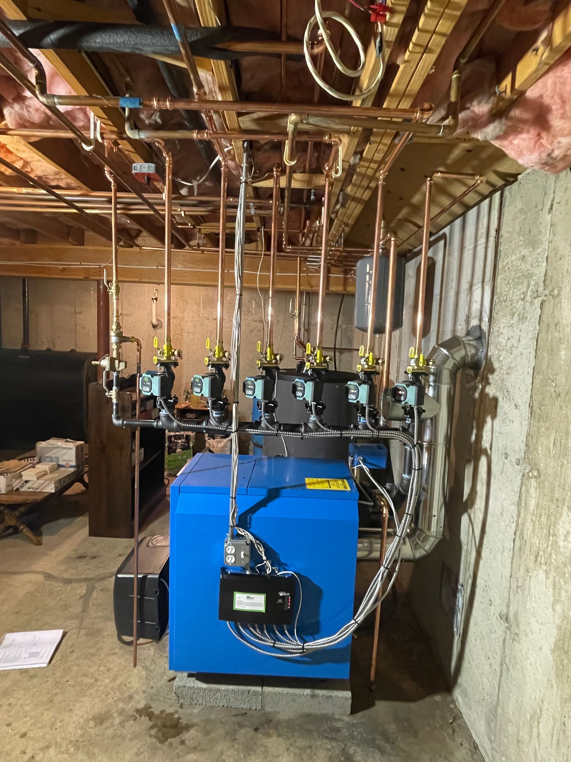 Blue boiler with copper pipes installed in a basement.