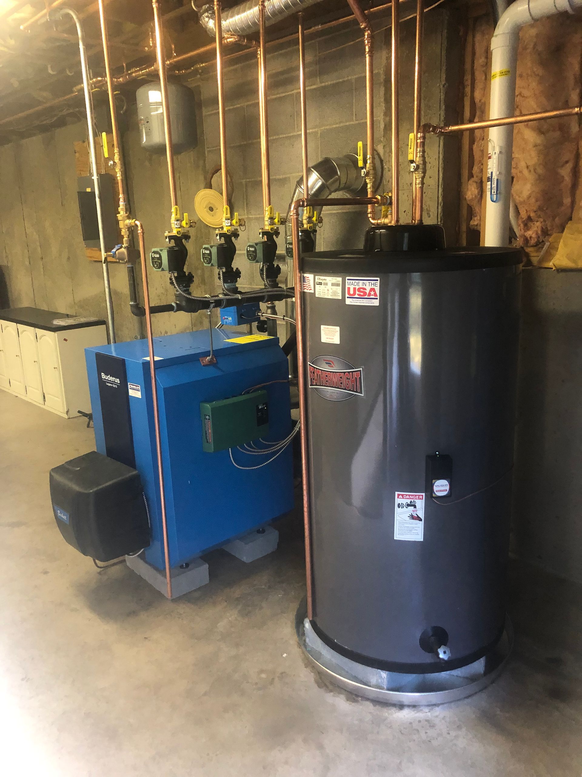 A blue boiler and a gray water heater are in a basement.