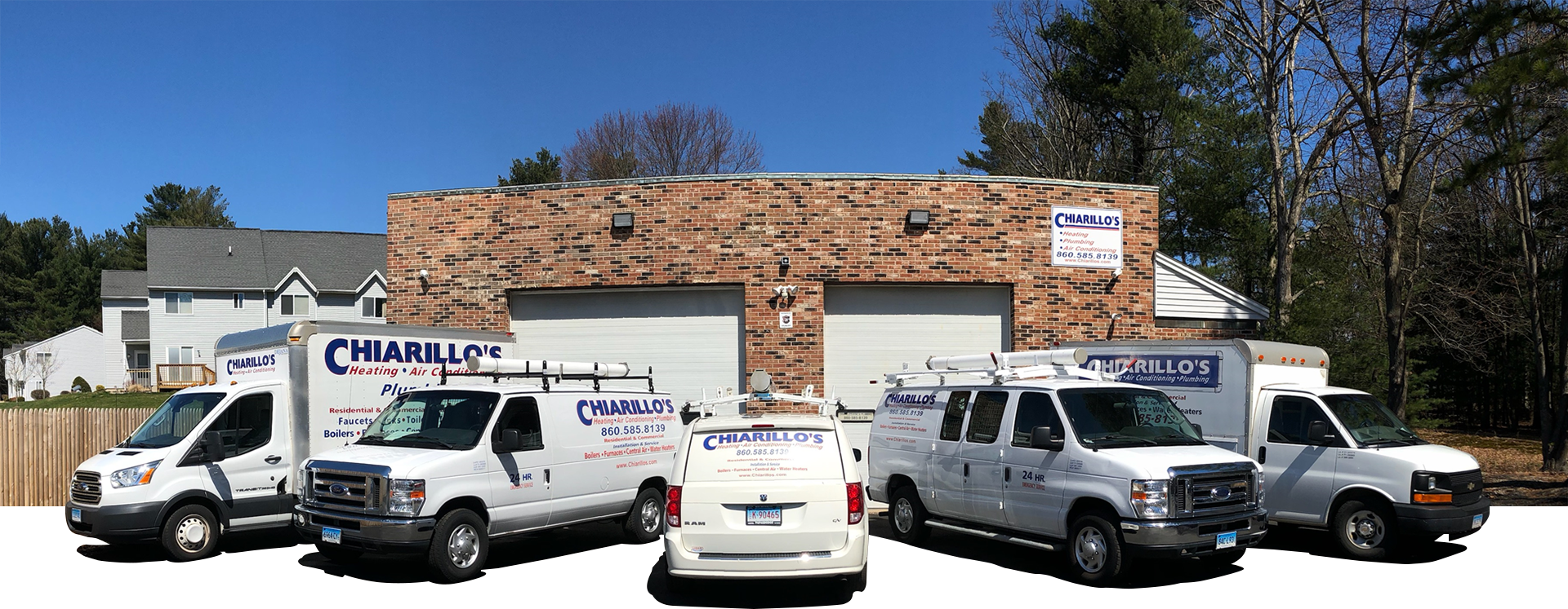 A group of white vans are parked in front of a brick building