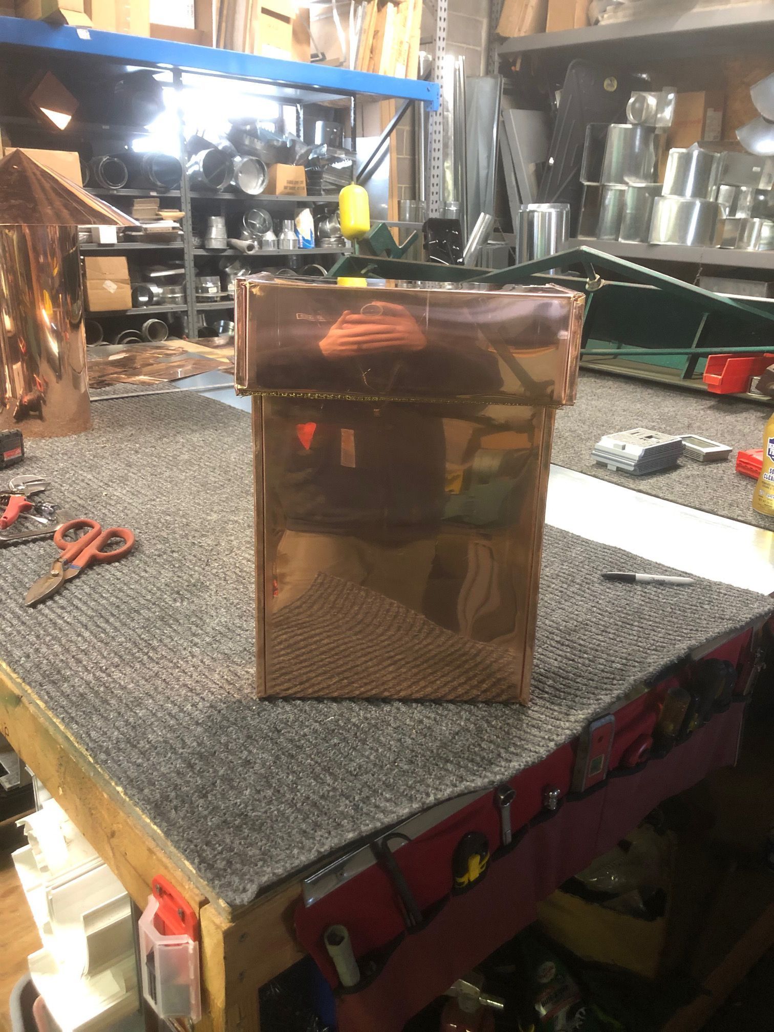 A copper box is sitting on top of a table in a workshop.