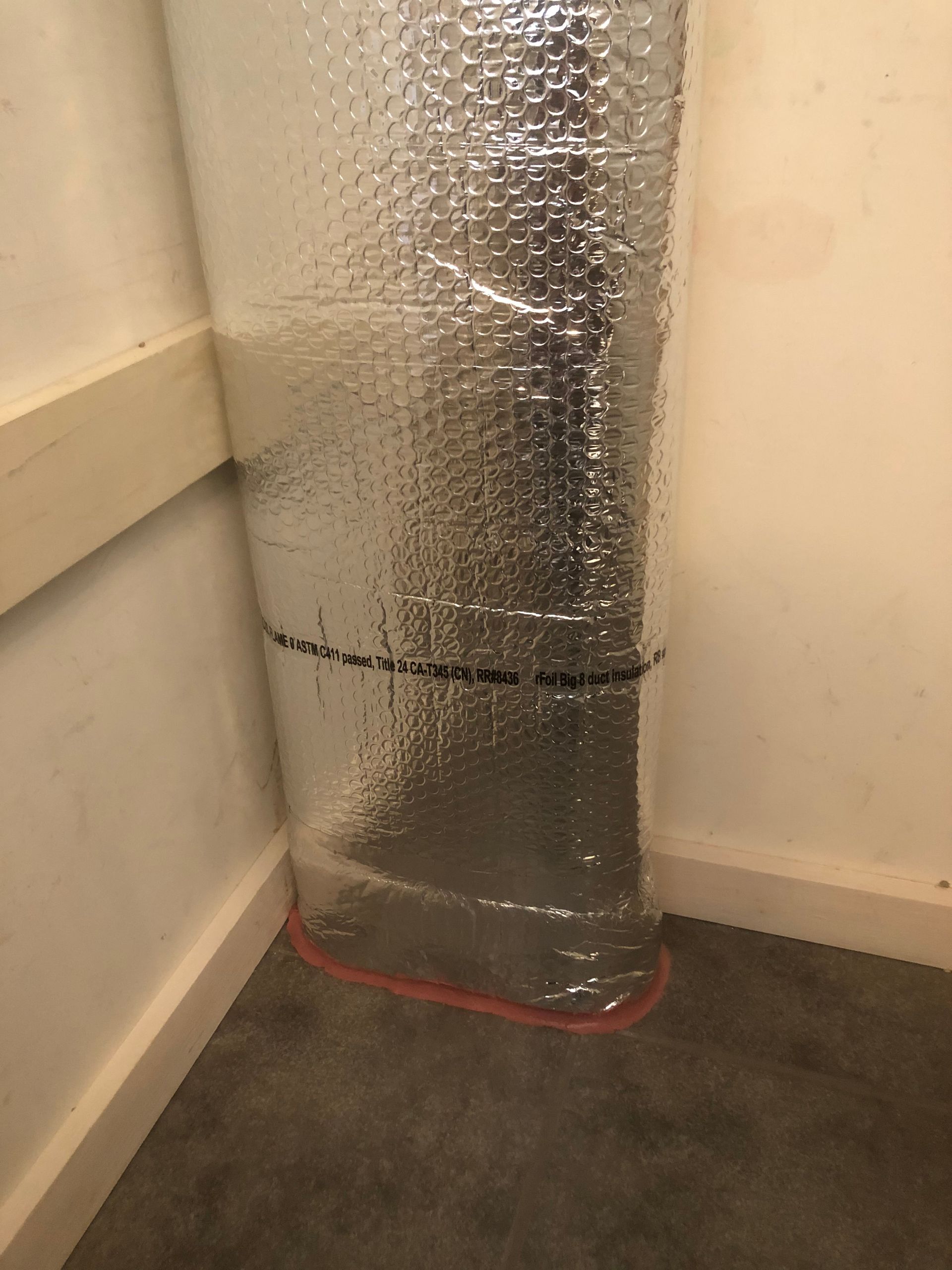 A piece of aluminum foil is wrapped around a pipe in a room.