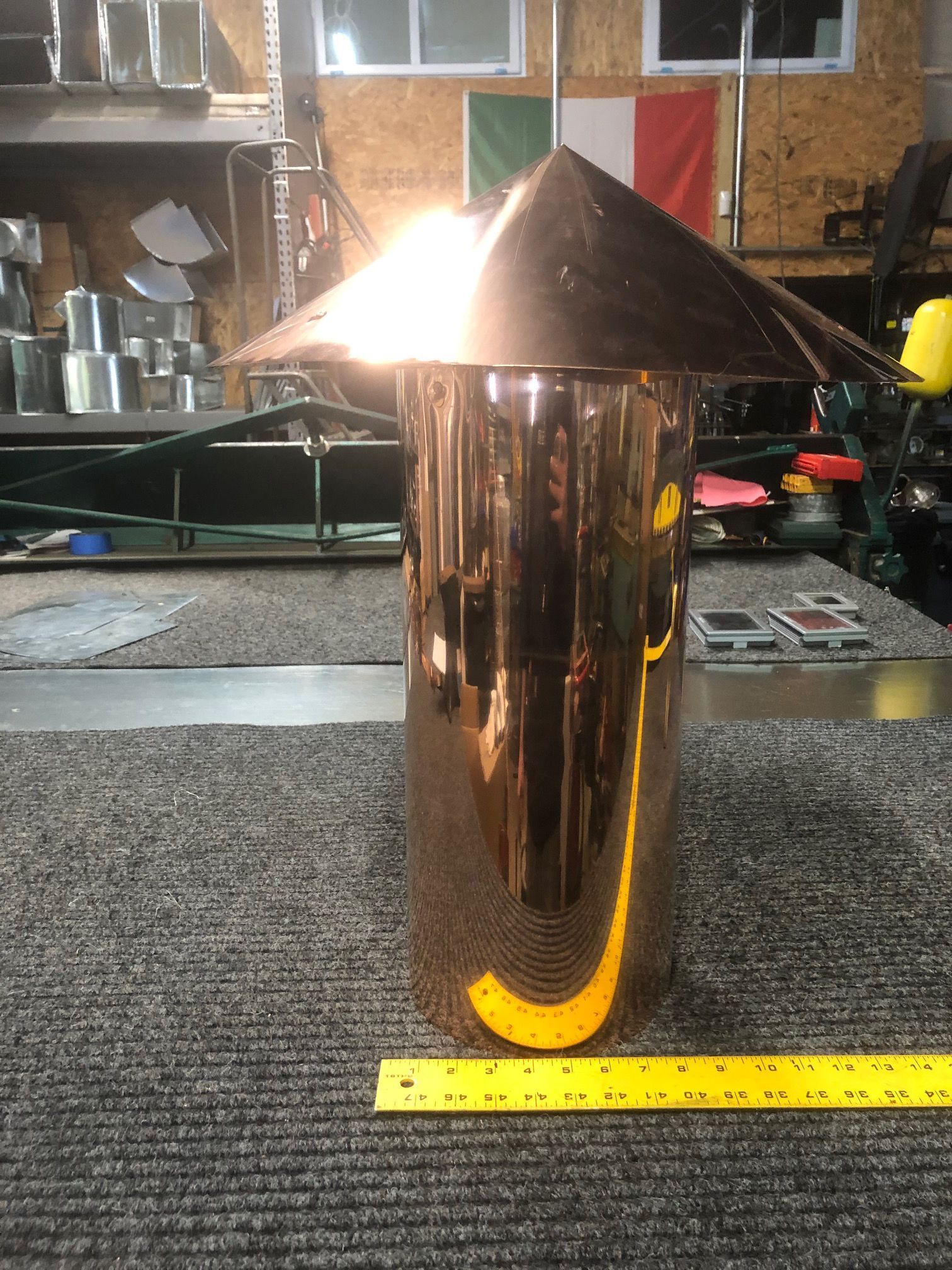 A copper object is sitting on a table next to a ruler