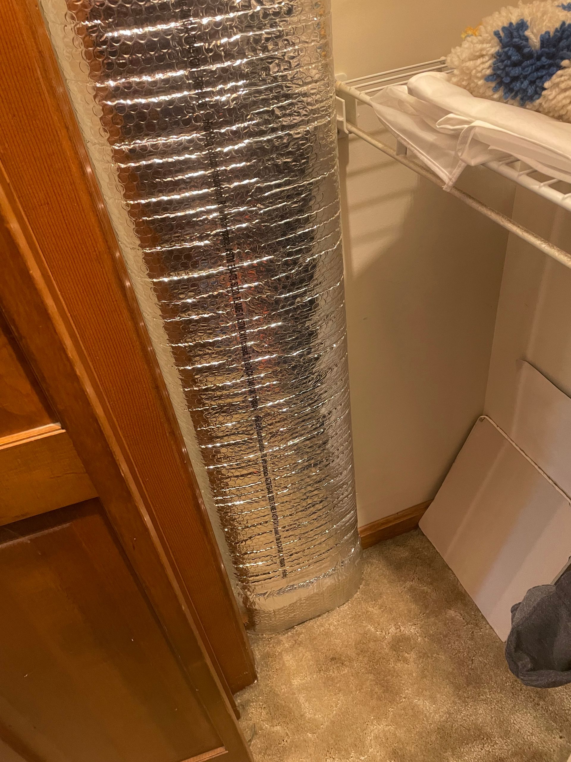 A large piece of aluminum foil is sitting on the floor in a closet.