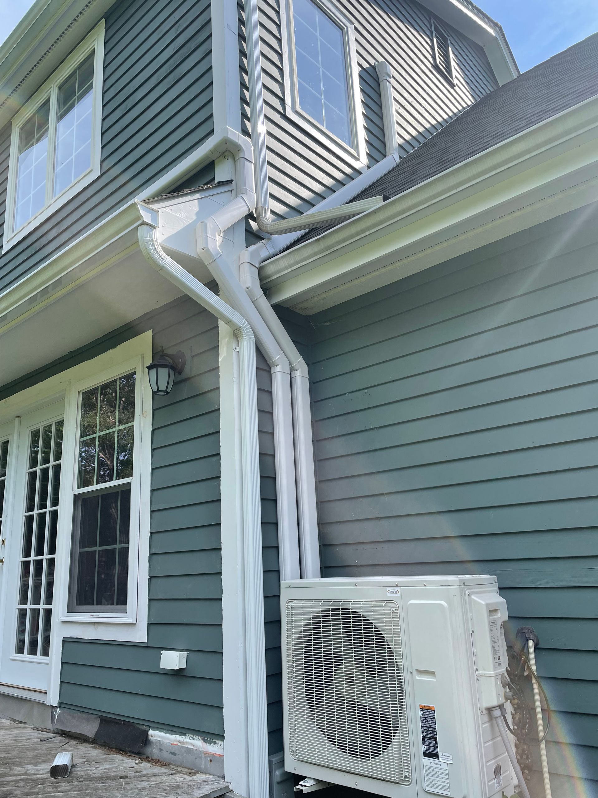 A white air conditioner is sitting on the side of a house.