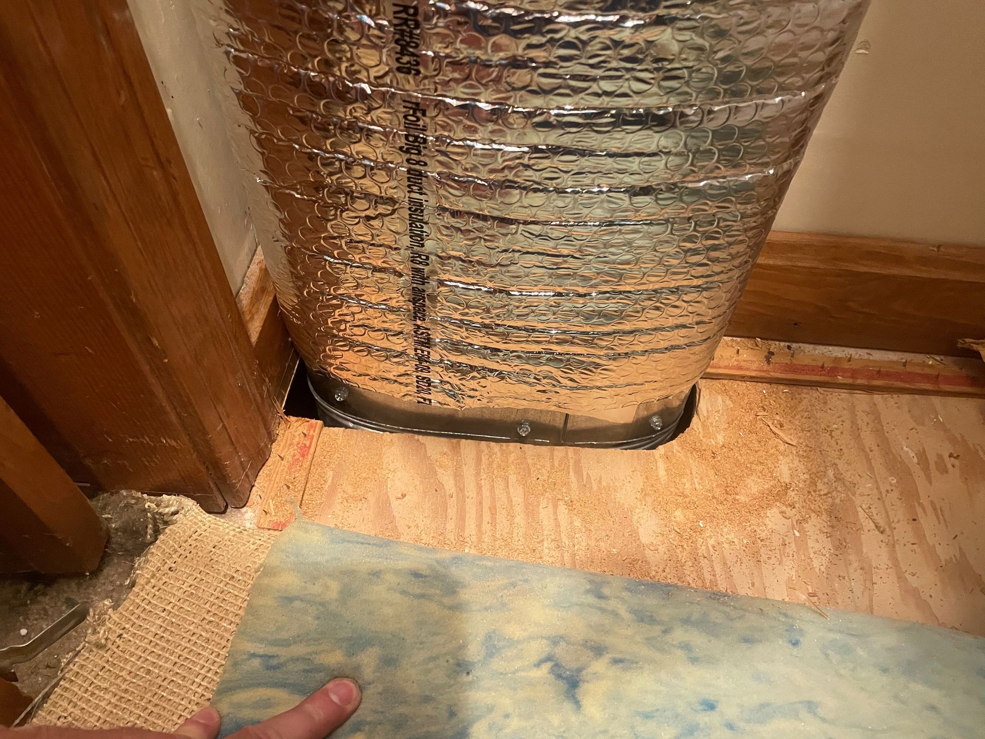 A person is pointing at a piece of insulation on the floor.