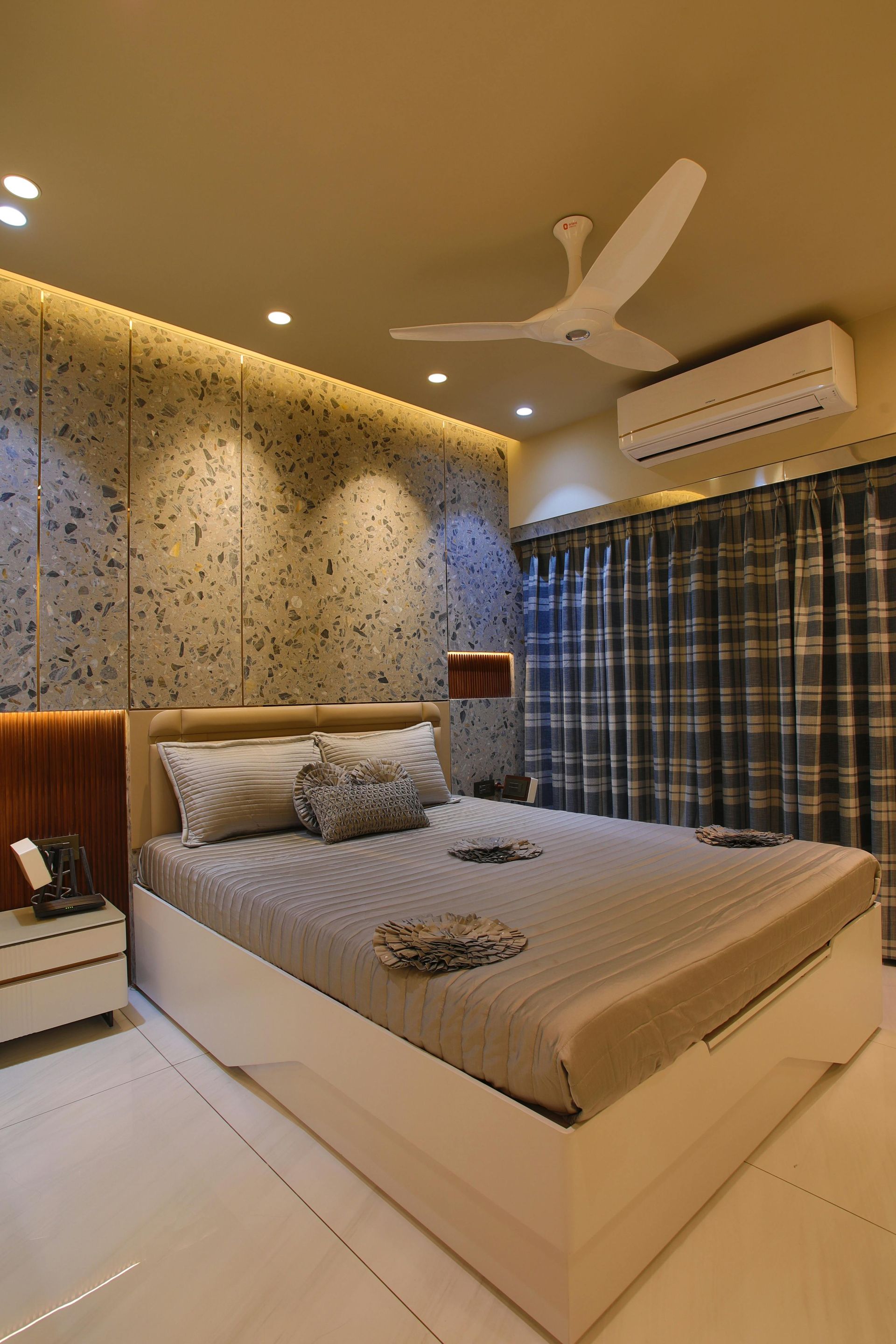 A bedroom with a large bed, an air conditioning system, and a ceiling fan.