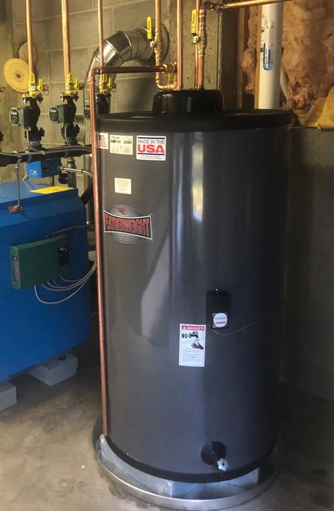 A large gray water heater is sitting in a room next to a blue boiler.