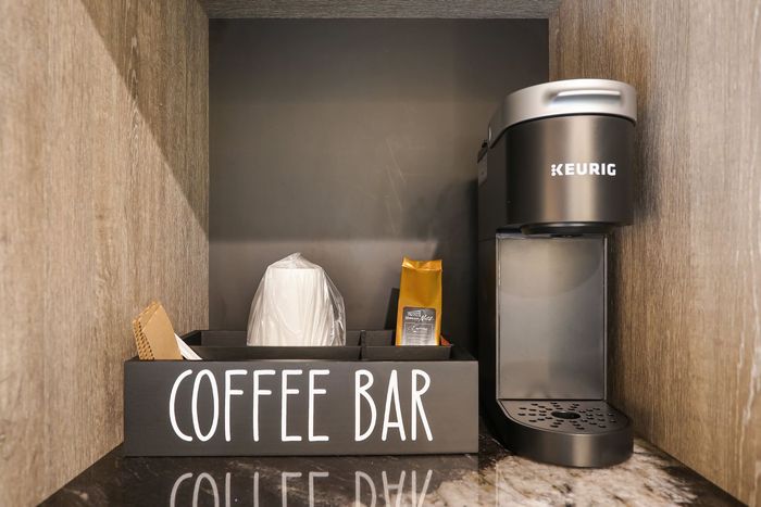 A coffee bar with a keurig coffee maker and a sign that says coffee bar.