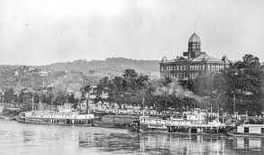 A black and white photo of a river with a large building in the background.