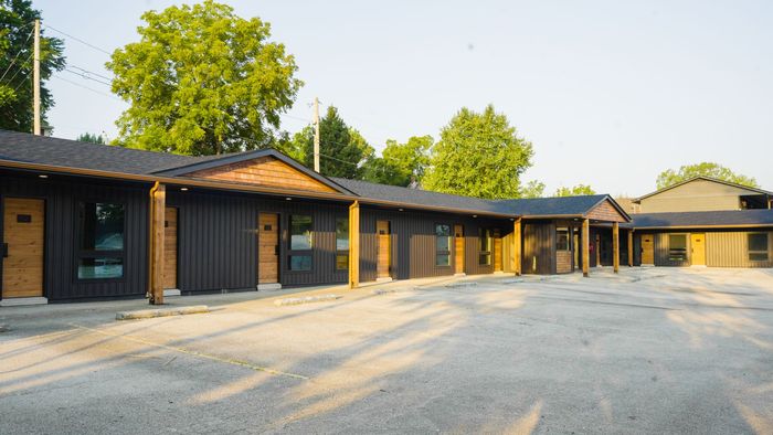 A motel with a lot of rooms and a parking lot in front of it.