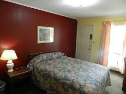 A hotel room with a bed , nightstand , lamp and window.