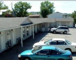 A couple of cars are parked in front of a motel.