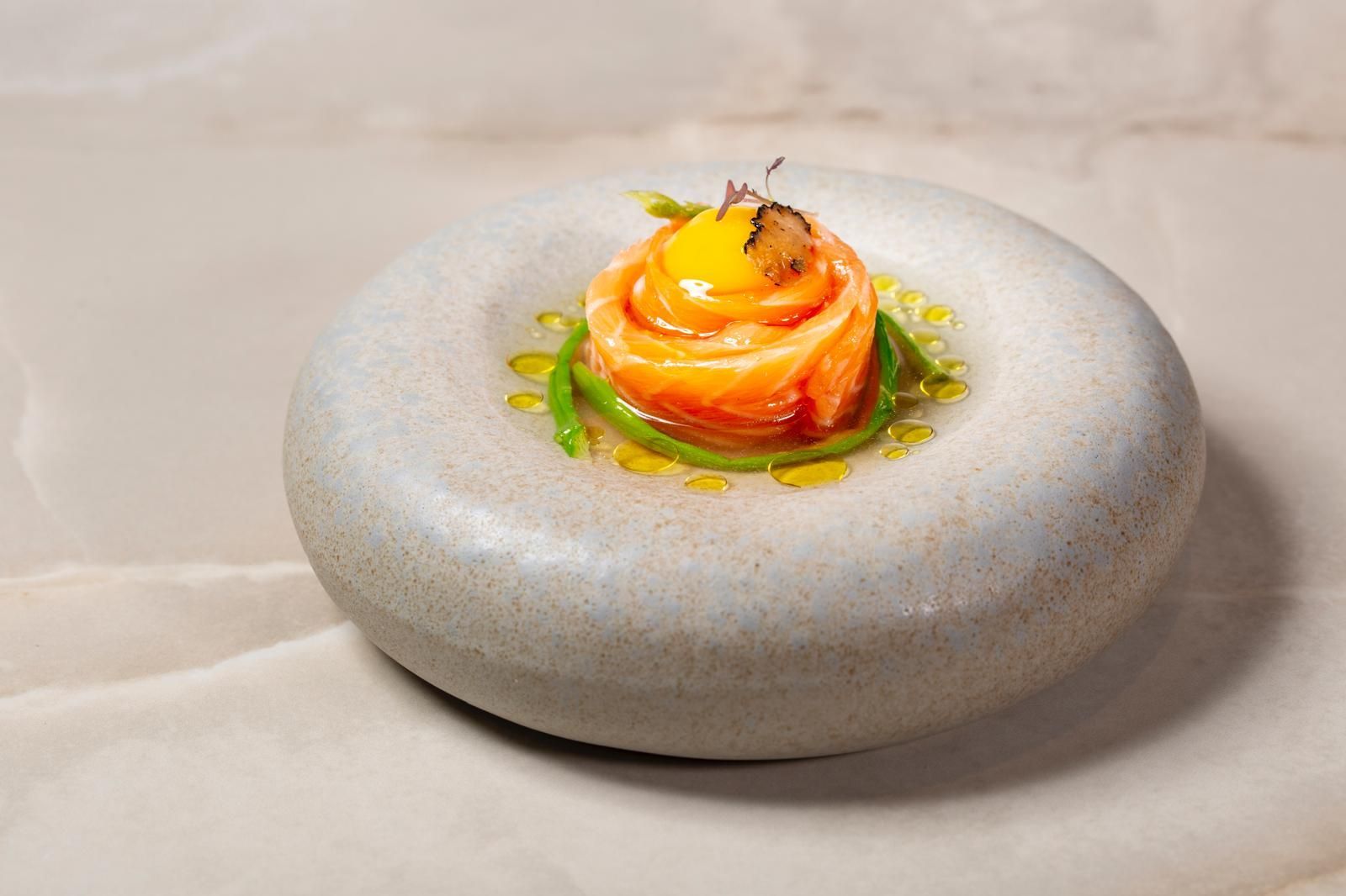 Una rosa di salmone sormontata da un tuorlo d'uovo crudo ed erbe aromatiche