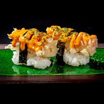 Un primo piano di un rotolo di sushi su un piatto verde su un tavolo.