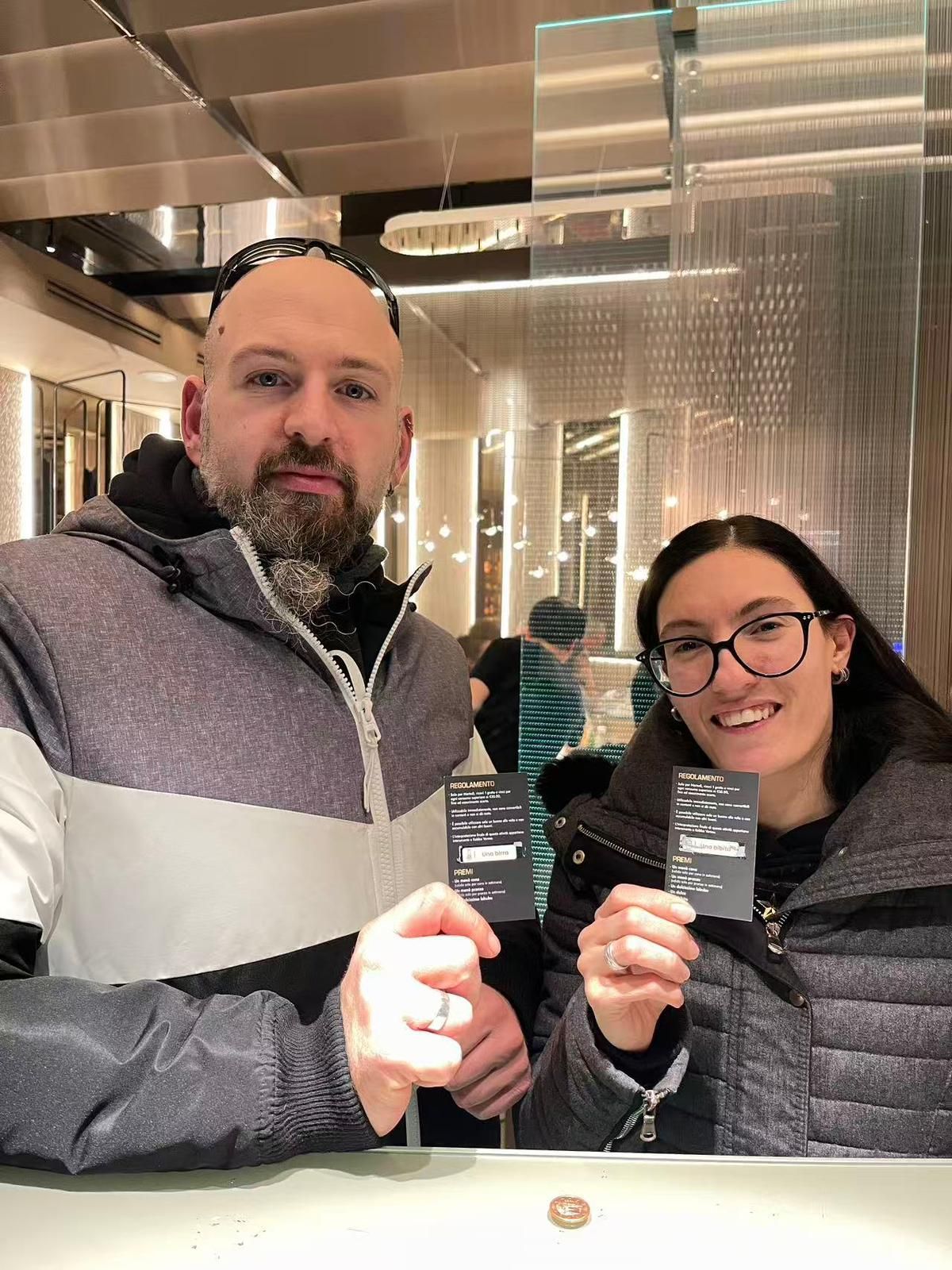 Due persone con indosso giacche invernali sono in piedi in uno spazio interno ben illuminato