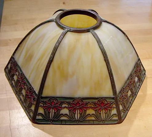 A stained glass lamp shade is sitting on a wooden table.