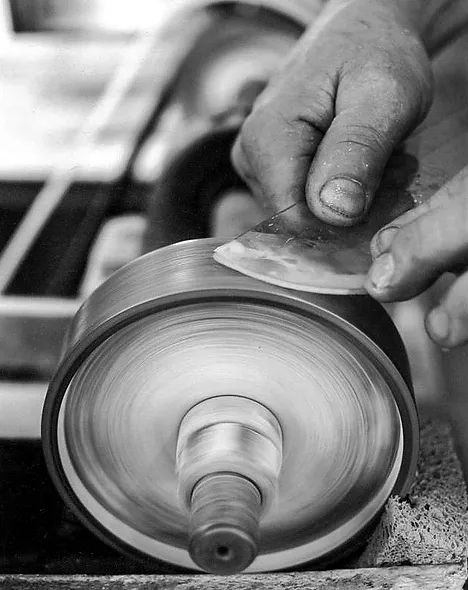 A black and white photo of a person polishing a piece of metal.