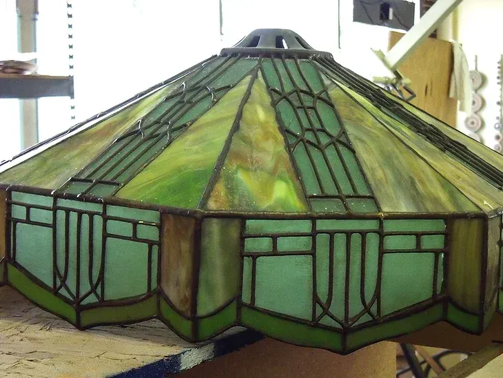 A green stained glass lamp shade is sitting on a table